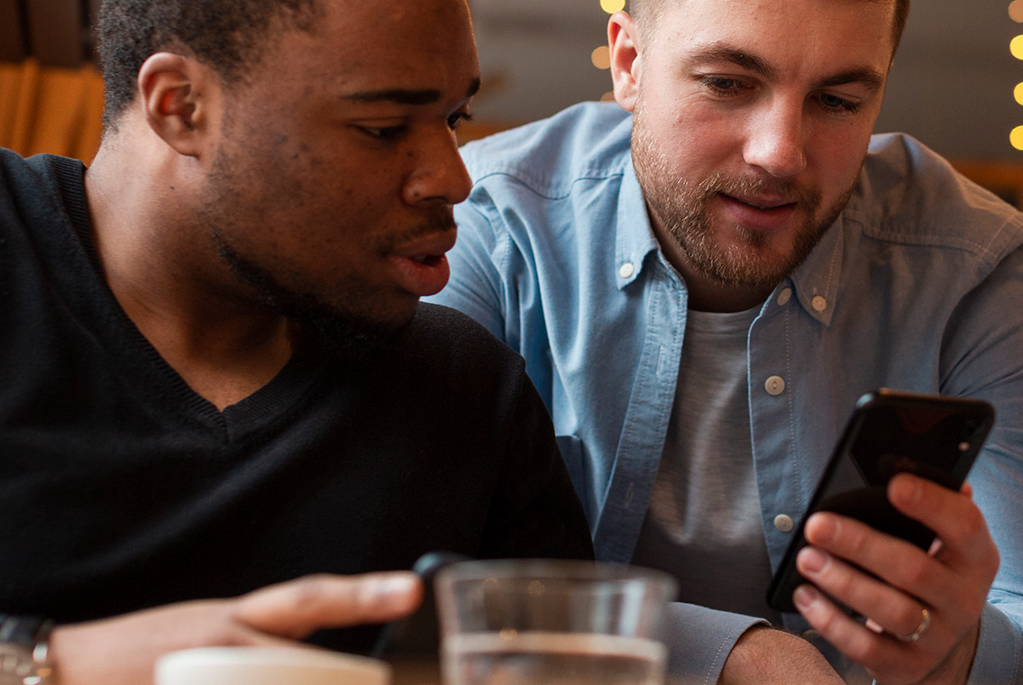 A photograph of two guys using a smartphone to find an NWA business with a Google search