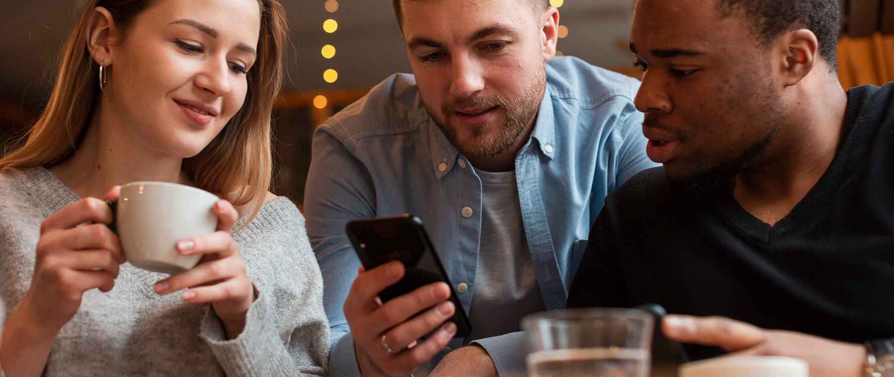 A photo of three people looking something up on their mobile phones